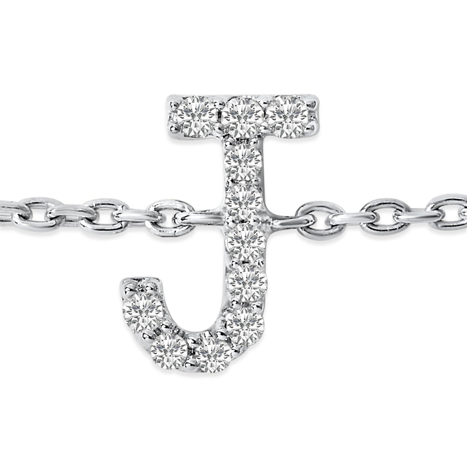 Close-up front view of a white metal bracelet featuring a 'J' shaped charm adorned with round white gemstones in a micro-pave setting, displayed on a white background.