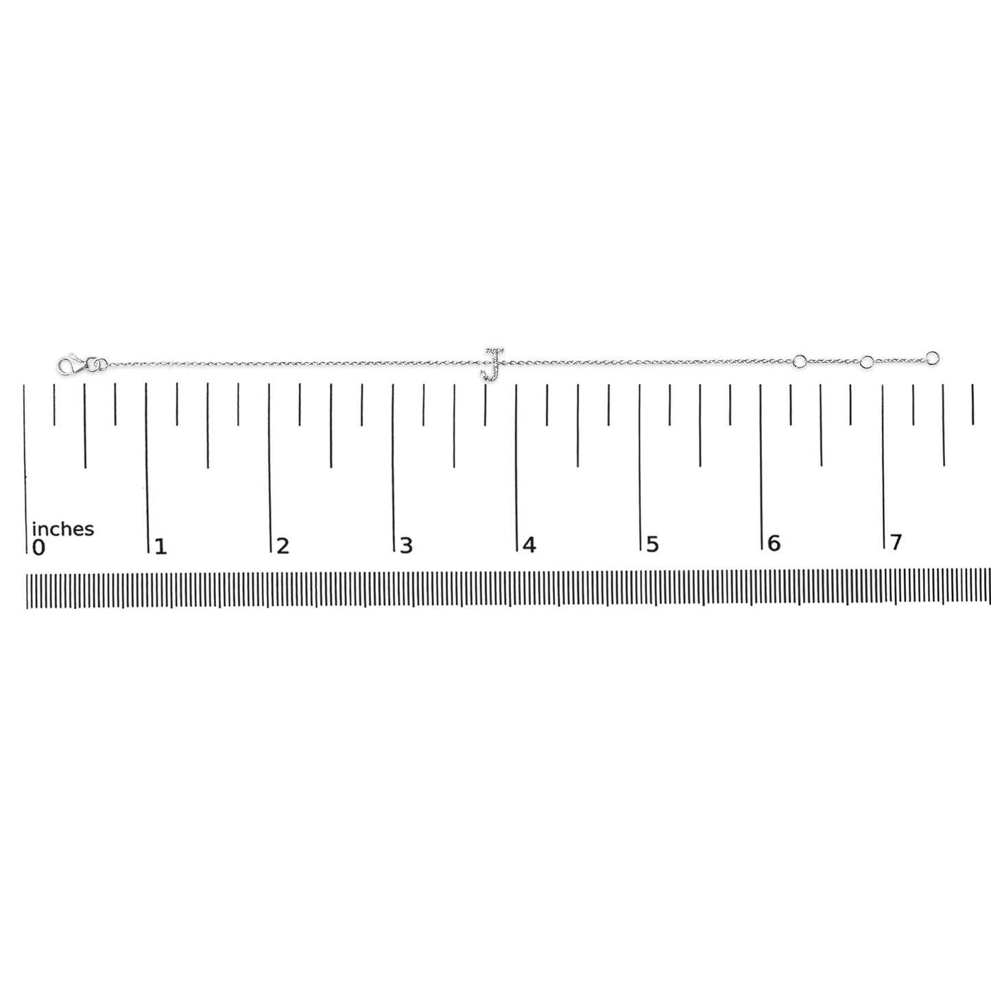Bracelet with a white metal chain and a letter 'J' centerpiece adorned with small white gemstones, shown flat on a ruler scale from a top-down angle.