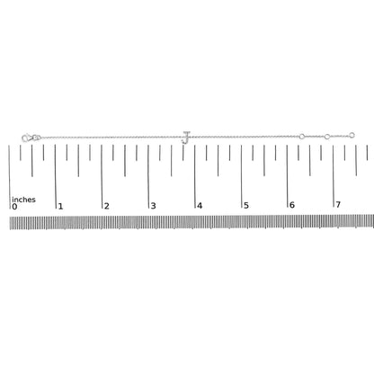 Bracelet with a white metal chain and a letter 'J' centerpiece adorned with small white gemstones, shown flat on a ruler scale from a top-down angle.