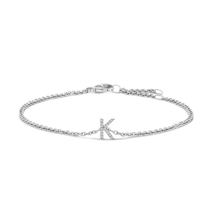 White metal bracelet with a chain design and a letter 'K' centerpiece adorned with small white gemstones, shown in a flat lay from the top angle.