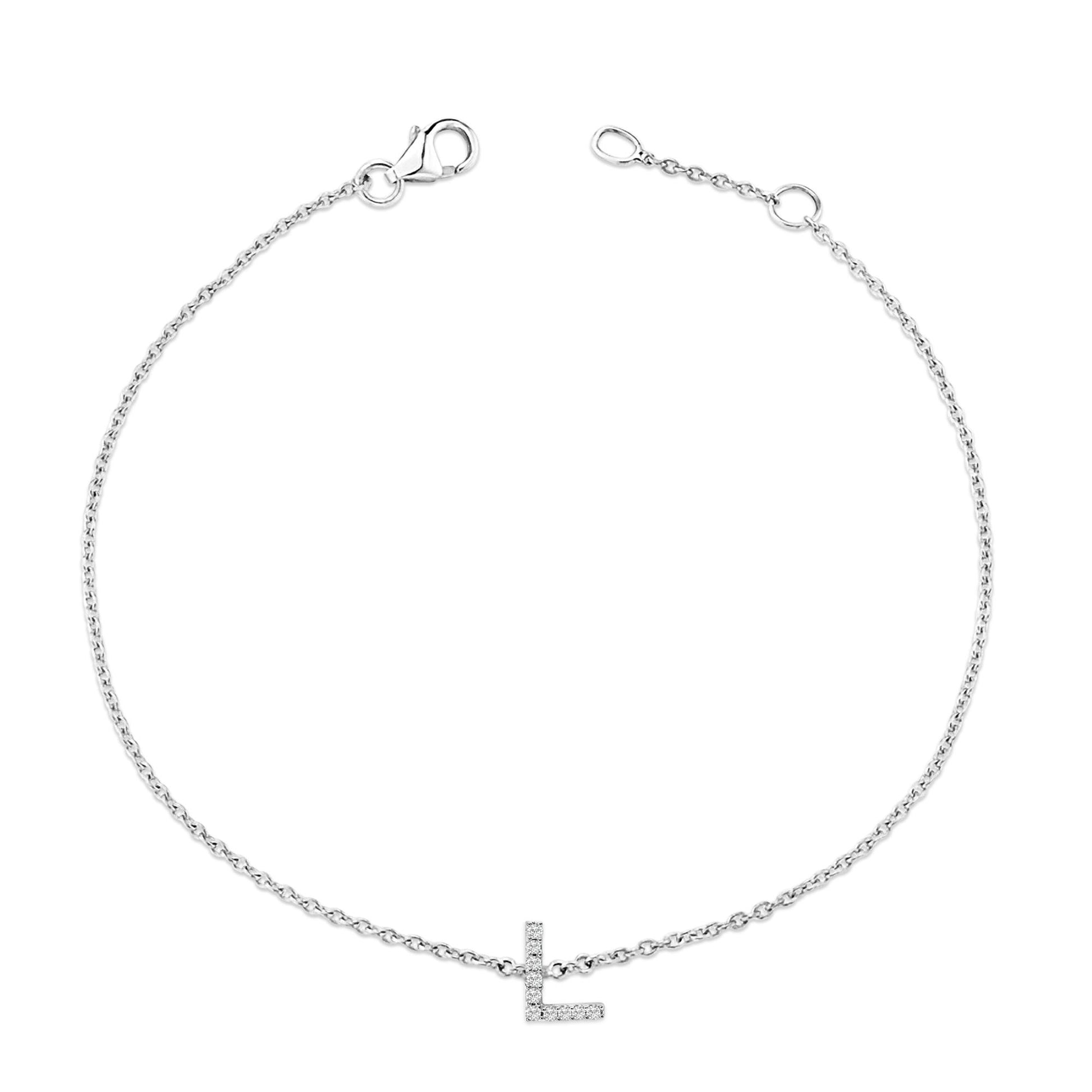 Close-up front view of a white metal bracelet with a delicate chain and an L-shaped charm adorned with small round white gemstones in micro-pave setting, shown on a white background.