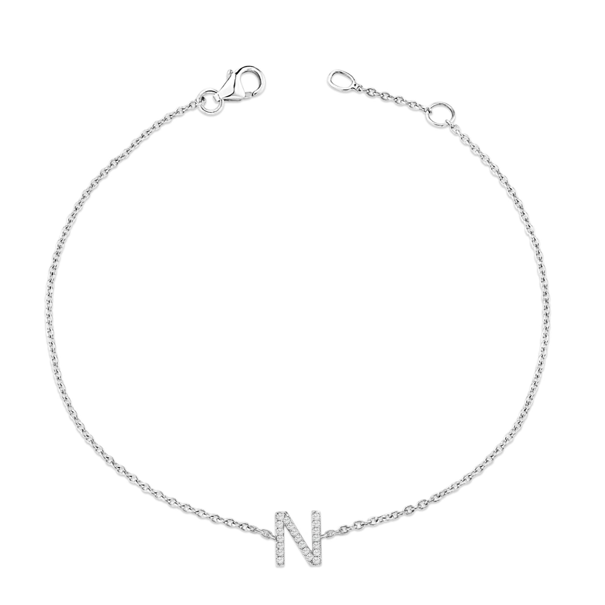 Bracelet with a delicate white chain and a letter 'N' charm adorned with small white gemstones in a micro-pave setting, shown flat from a top-down angle.