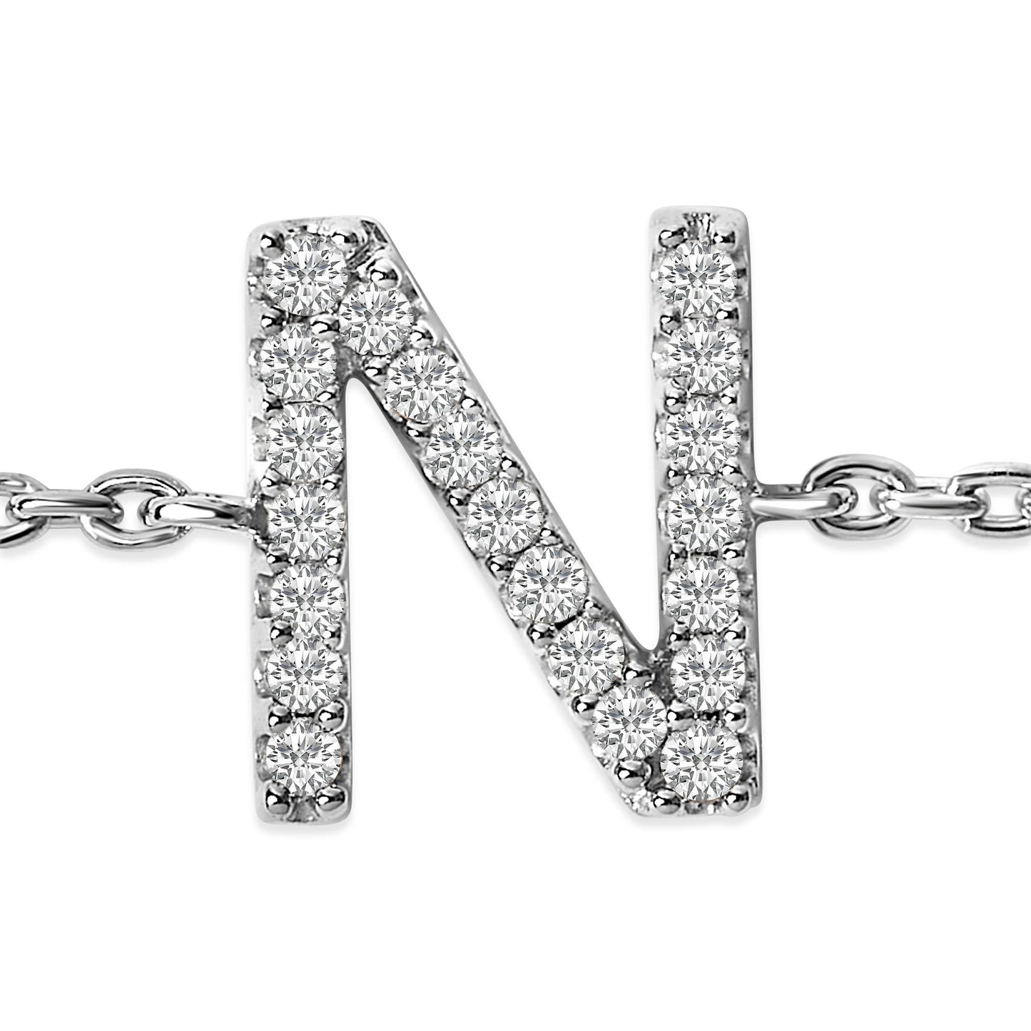 Close-up front view of a white metal bracelet with a letter N charm adorned with round white gemstones in micro-pave setting, attached to a chain.