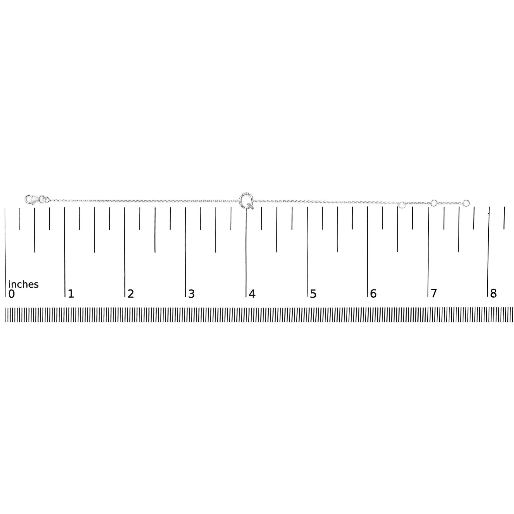 White metal bracelet with a round center element set with small white gemstones, shown on a ruler scale from a top-down angle.