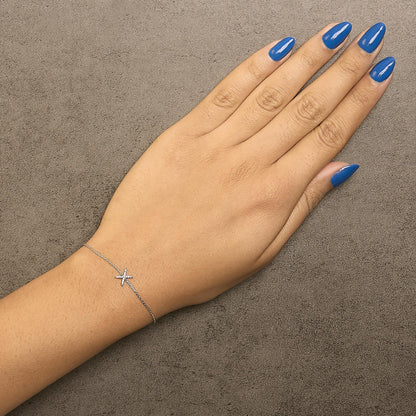 Bracelet with a small star-shaped charm set with white gemstones on a delicate white chain, shown worn on a model's wrist from a top-down angle.