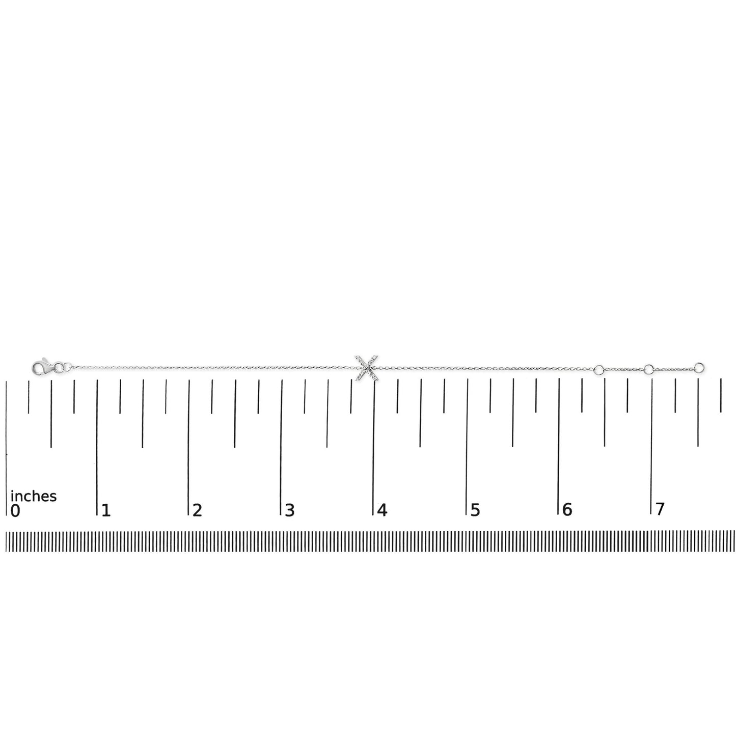 White bracelet with a chain and an X-shaped centerpiece featuring small white gemstones in a micro-pave setting, shown flat on a ruler for scale, viewed from above.