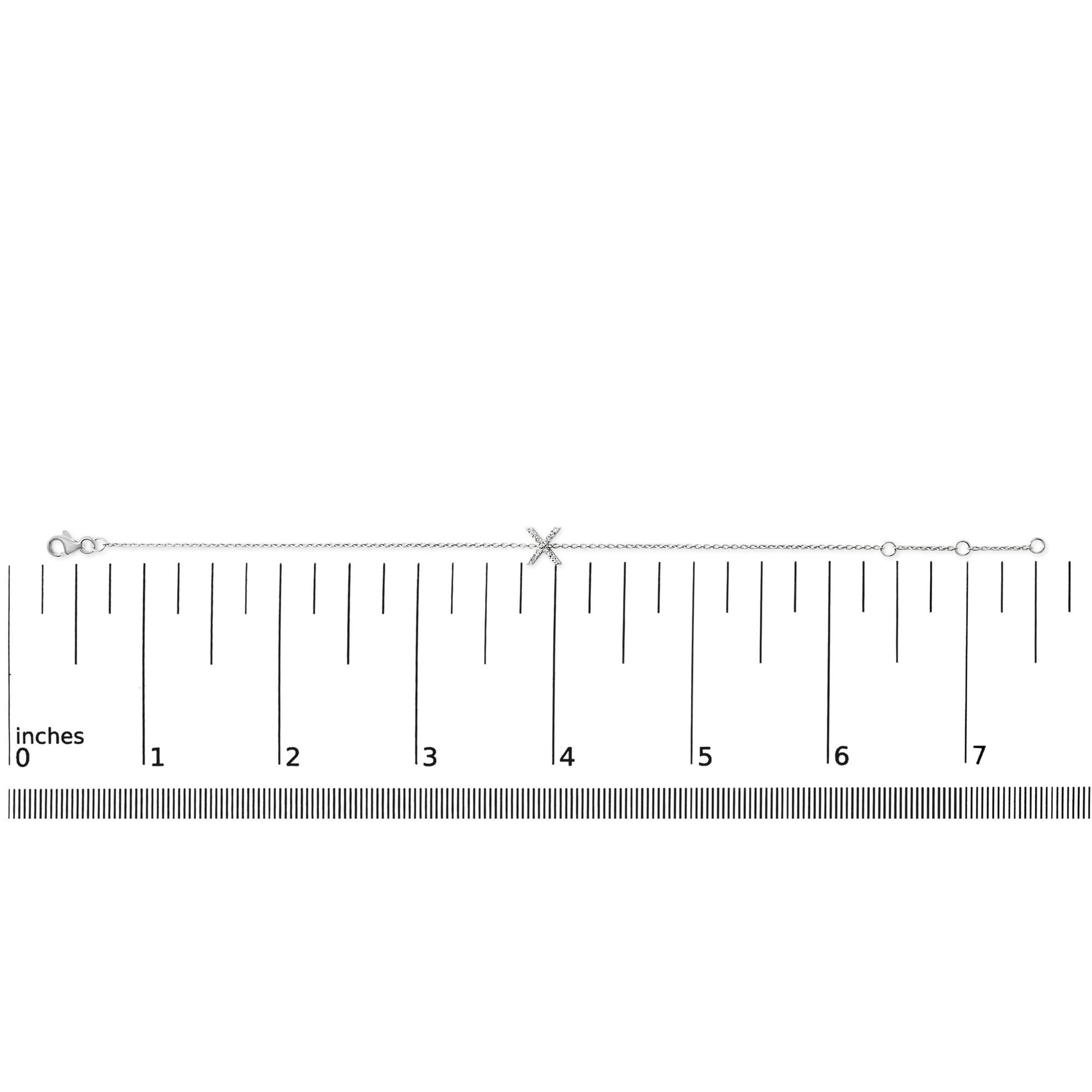 White bracelet with a chain and an X-shaped centerpiece featuring small white gemstones in a micro-pave setting, shown flat on a ruler for scale, viewed from above.