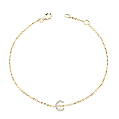 Yellow metal bracelet with a delicate chain and a curved charm set with small white gemstones, shown flat against a white background from a top-down angle.