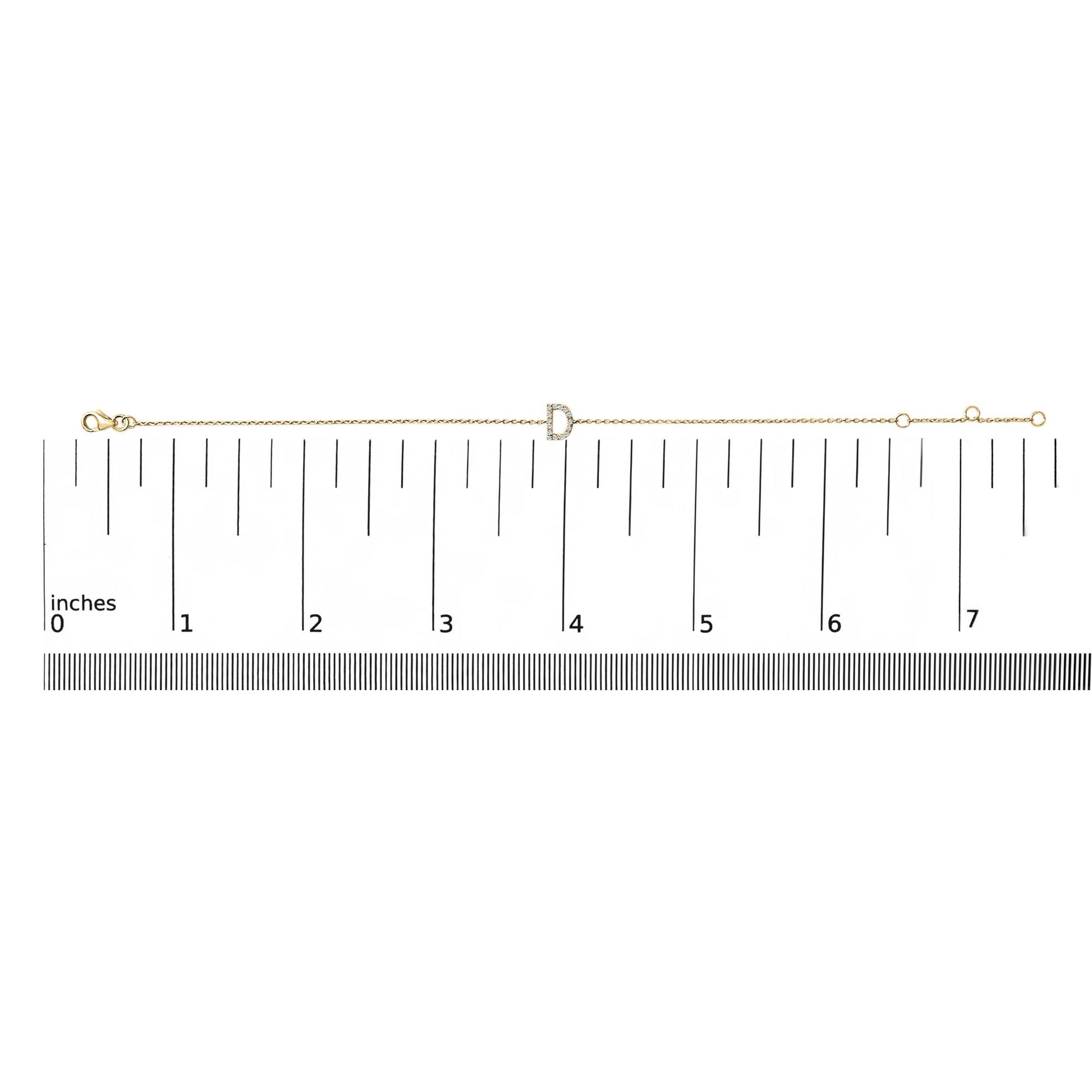 Yellow bracelet with a letter-shaped centerpiece adorned with small white gemstones in a micro-pave setting, displayed on a scale from a top-down angle.
