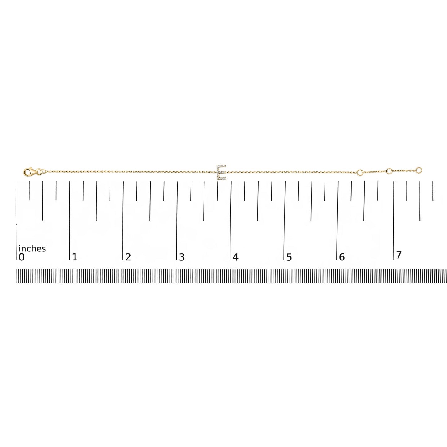 Yellow bracelet with a letter-shaped centerpiece adorned with small white gemstones in micro-pave setting, shown laid flat on a ruler from a top-down angle.