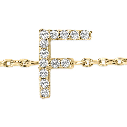 Close-up front angle of a yellow metal bracelet featuring an 'F' shaped charm adorned with round white gemstones in a micro-pave setting, shown on a white background.