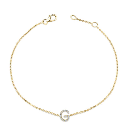 Yellow metal bracelet with a circular link chain and a central letter-shaped charm embellished with small white gemstones, shown flat from a top-down angle.