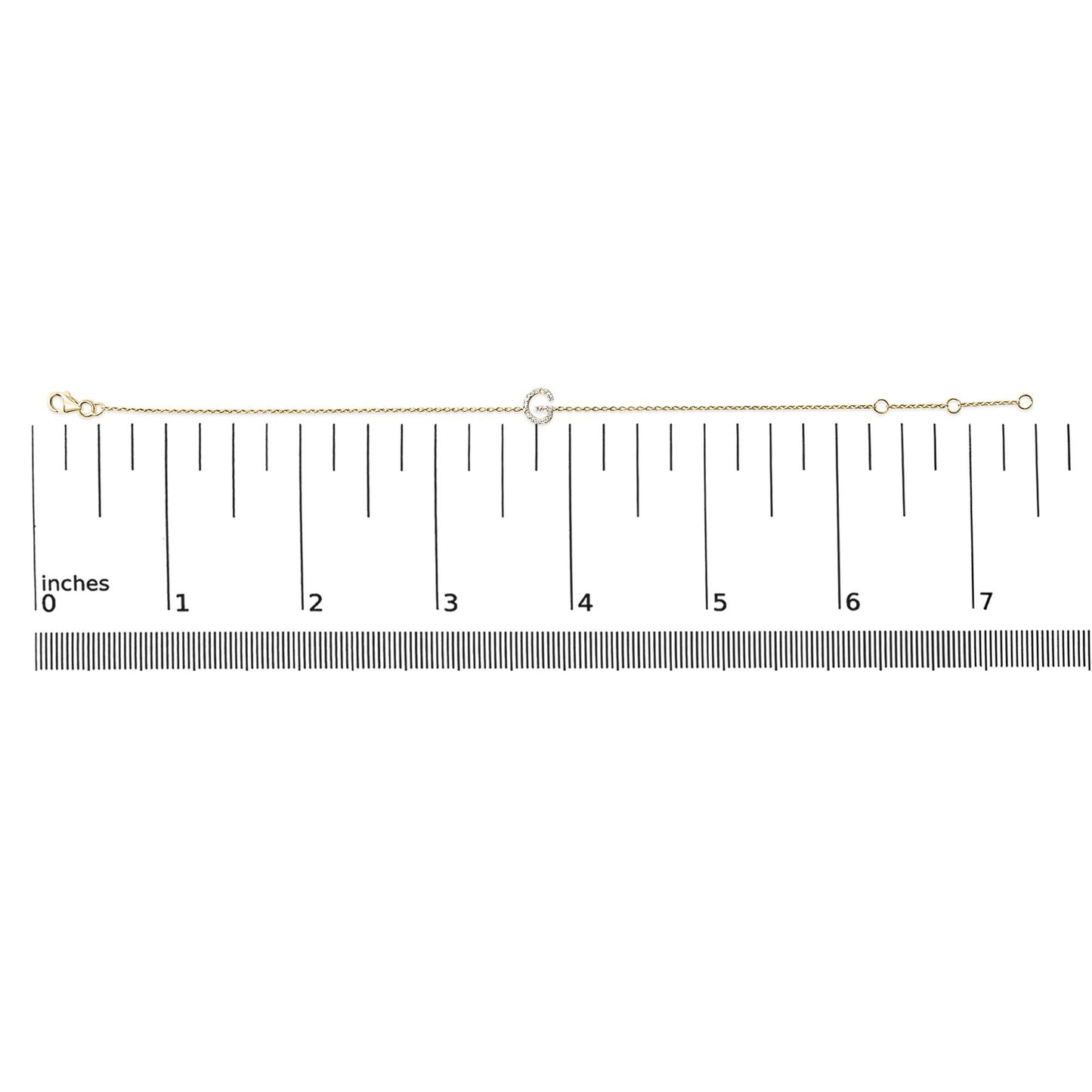 Yellow metal bracelet with a small circular charm encrusted with white gemstones, shown flat on a ruler scale in a top-down angle.