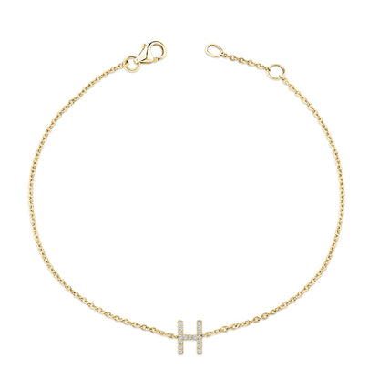 Yellow metal bracelet with a delicate chain and a horizontal bar pendant shaped like the letter H, set with small white gemstones in a micro-pave setting, shown from a top-down angle.