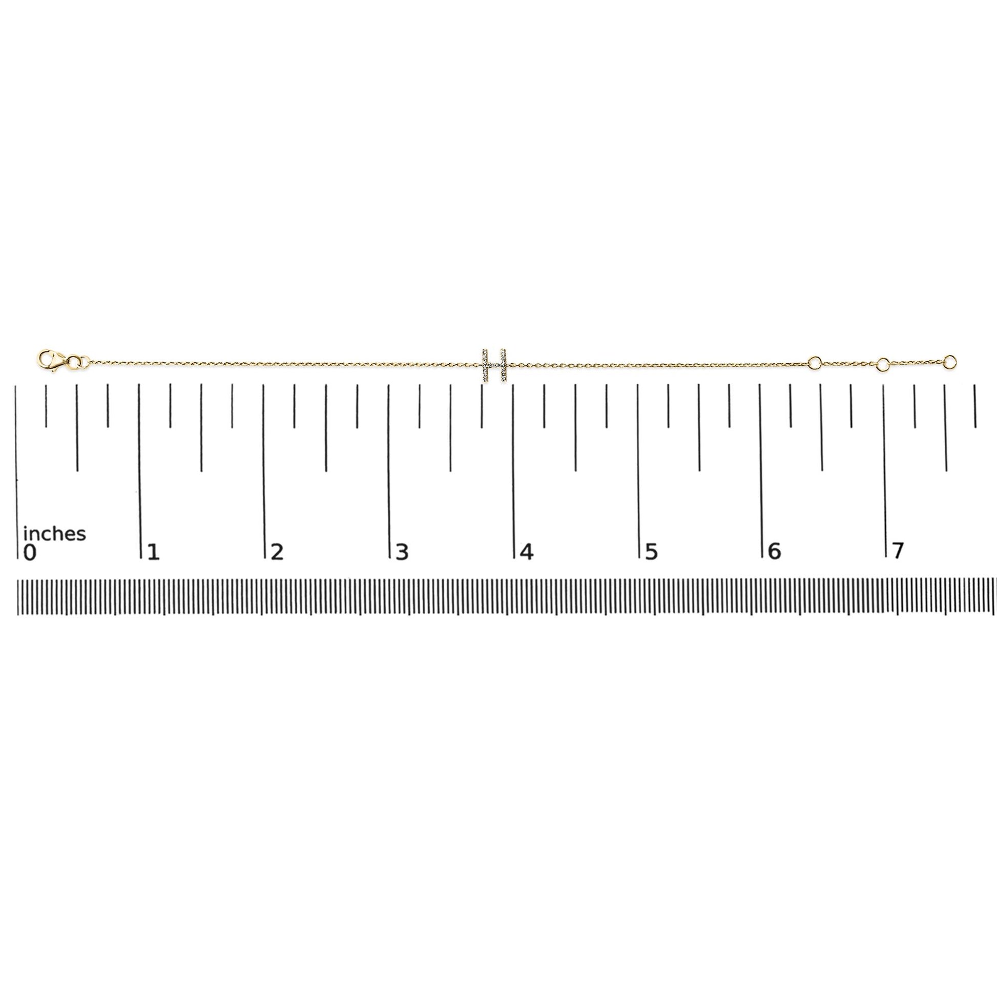 Yellow metal bracelet with a double bar centerpiece featuring small white gemstones in a micro-pave setting, shown on a scale from a top view.