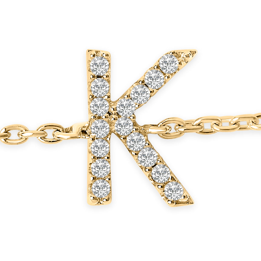 Close-up front view of a yellow metal bracelet featuring a letter 'K' pendant adorned with round white gemstones in a micro-pave setting.