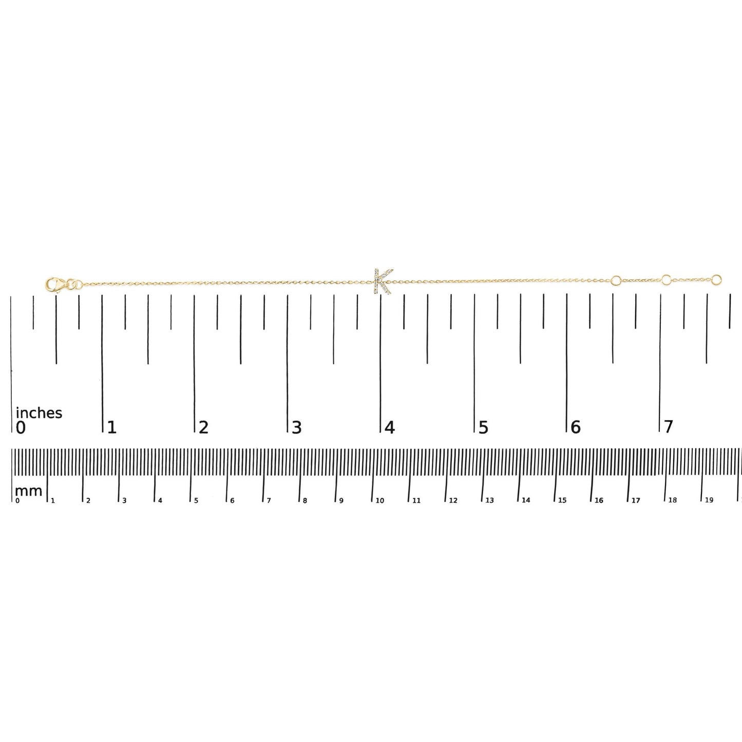 Yellow bracelet with a chain design featuring a letter adorned with small white gemstones, shown on a scale from a top-down angle.