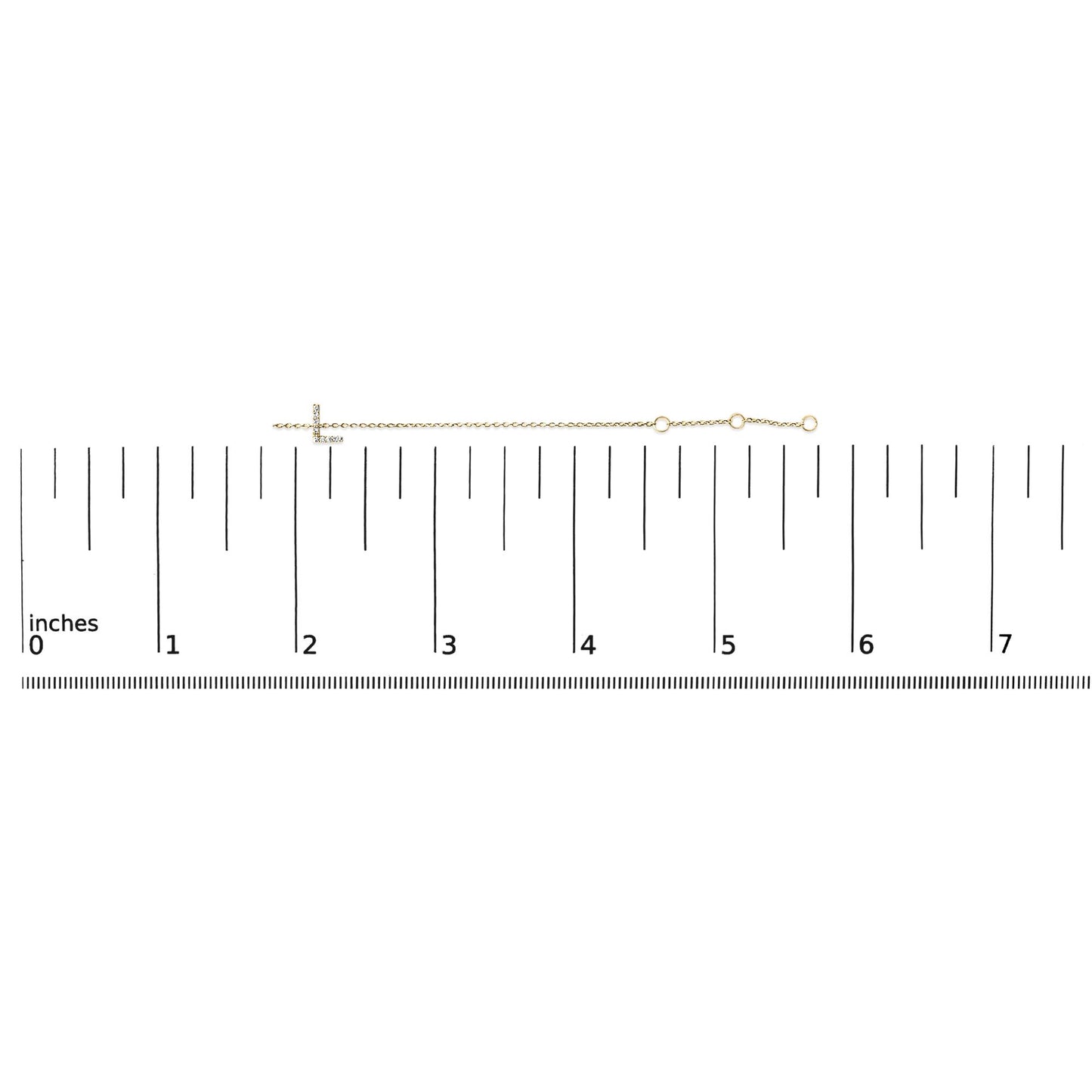 Yellow metal bracelet with a horizontal cross featuring small white gemstones in a micro-pave setting, shown on a scale from a top-down angle.