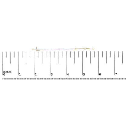 Yellow metal bracelet with a horizontal cross featuring small white gemstones in a micro-pave setting, shown on a scale from a top-down angle.