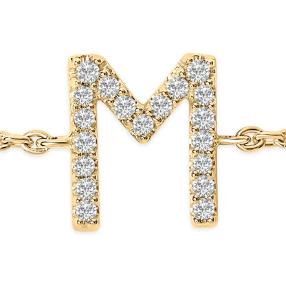 Close-up front view of a yellow metal bracelet featuring an 'M' shaped charm adorned with round white gemstones in a micro-pave setting.