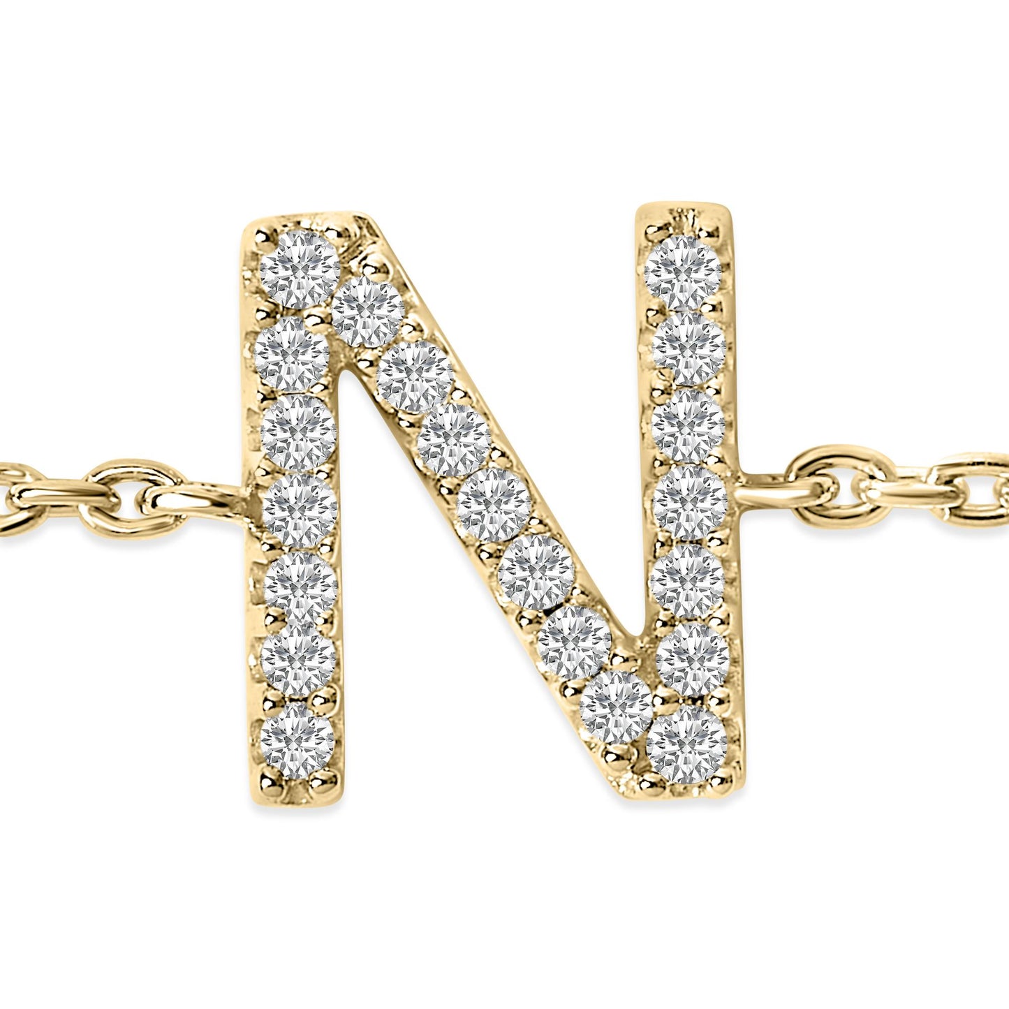 Close-up front view of a yellow metal bracelet featuring an uppercase letter 'N' pendant adorned with round white gemstones in a micro-pave setting, shown flat on a white background.