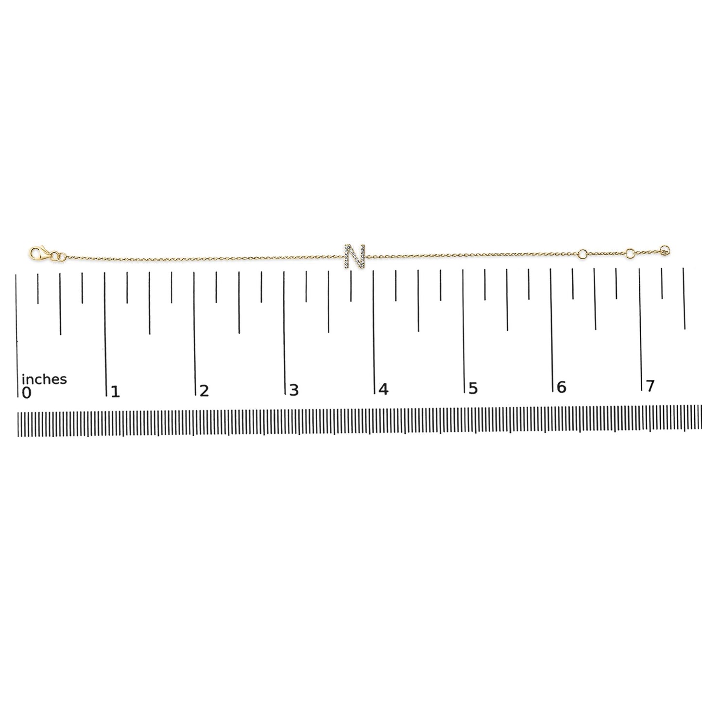 Thin yellow bracelet with a central letter 'N' adorned with small white gemstones in a micro-pave setting, shown on a scale from a top-down angle.