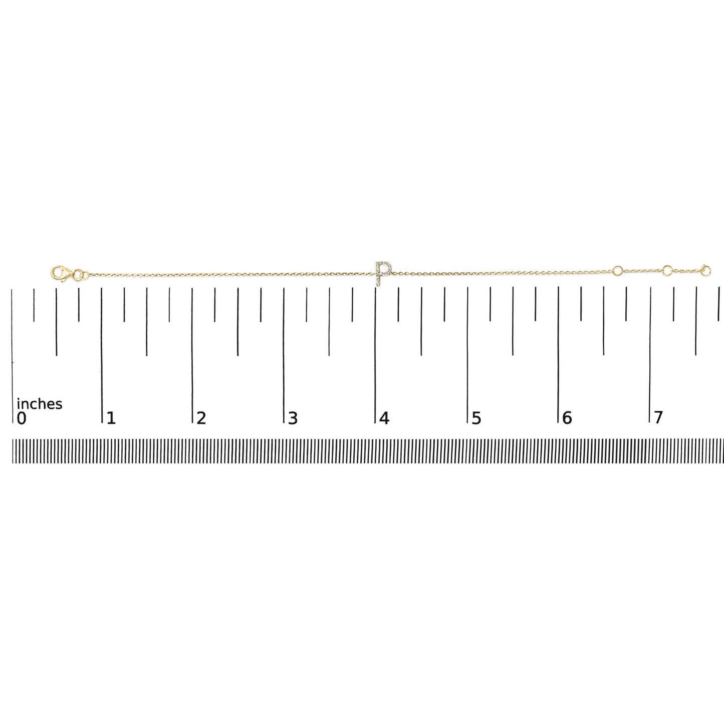 Yellow metal bracelet with a micro-pave set white gemstone initial charm, shown on a ruler scale from a top-down angle.