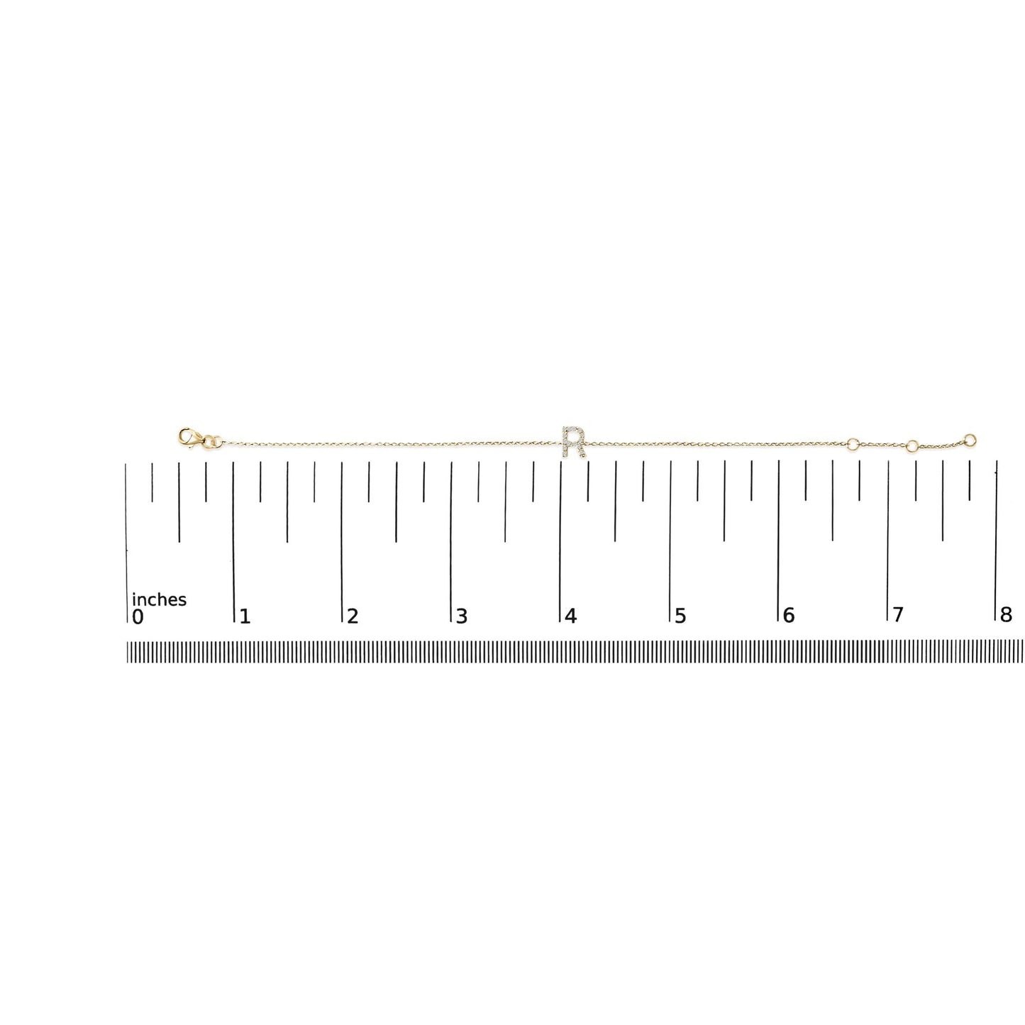 Yellow bracelet with a central letter 'R' set with small white gemstones in a micro-pave setting, displayed flat on a measurement scale, top-down angle.