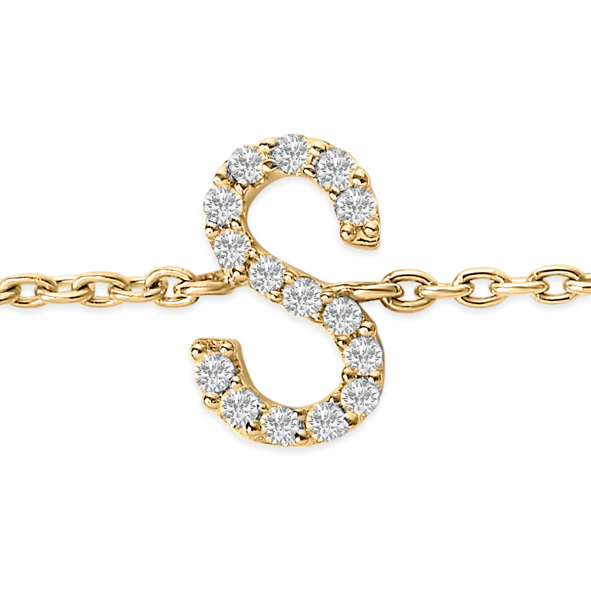 Close-up front view of a yellow metal bracelet featuring an 'S' shaped charm adorned with round white gemstones in a micro-pave setting.