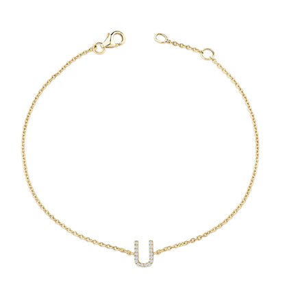Top-down view of a yellow metal chain bracelet with a U-shaped charm adorned with small white gemstones in a micro-pave setting.