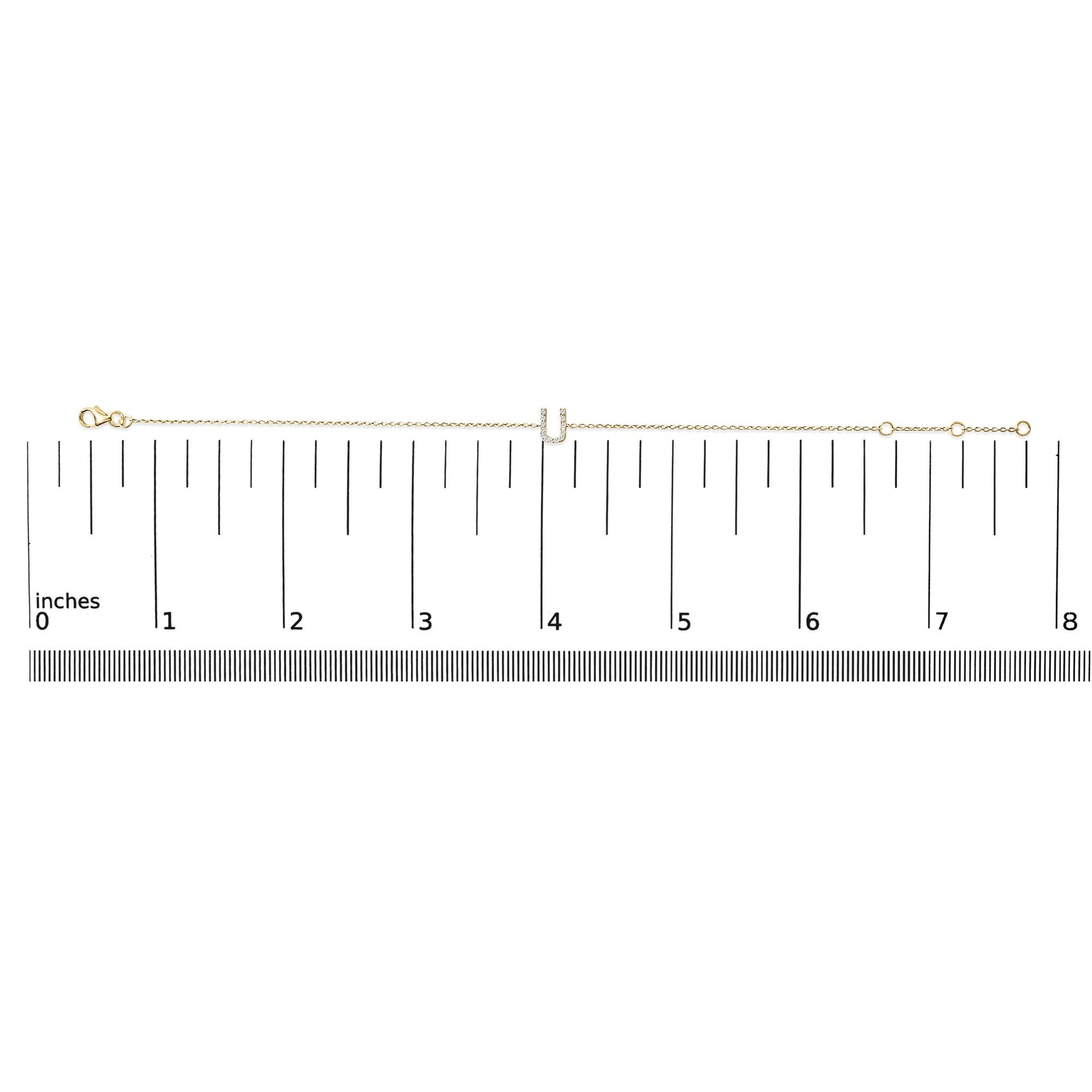 Yellow bracelet with chain and U-shaped centerpiece featuring white gemstones in a micro-pave setting, shown flat on a scale from above.