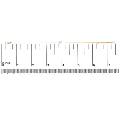 Yellow metal bracelet with a delicate chain and a small 'Y' shaped charm featuring white gemstones, shown flat on a ruler measuring approximately 7 inches, top-down angle.