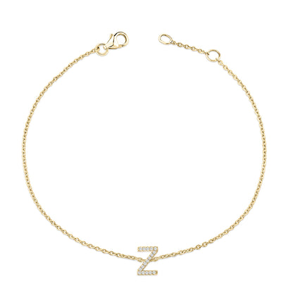Yellow bracelet with a chain and a central Z-shaped charm adorned with small white gemstones in a micro-pave setting, shown from a top-down angle on a white background.