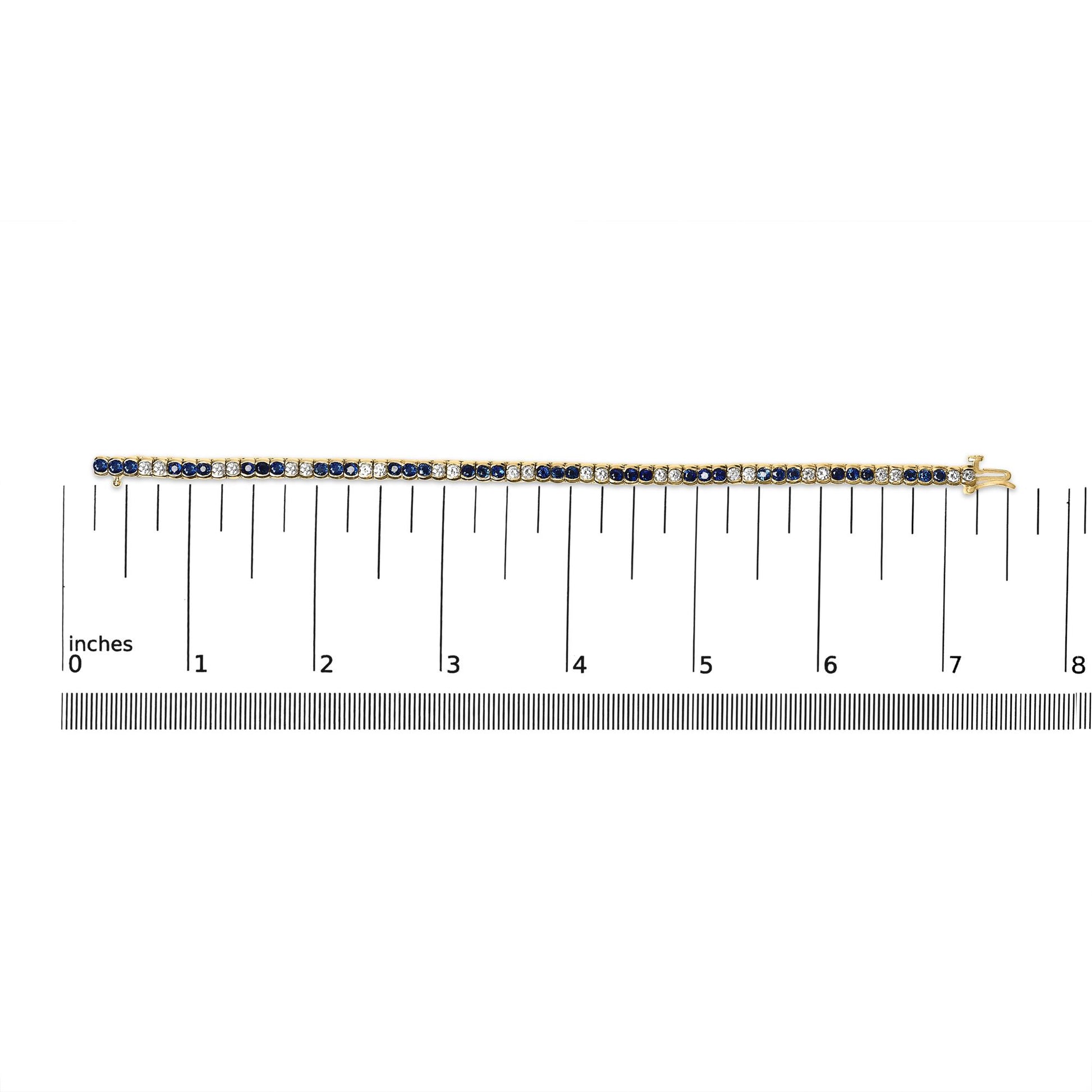 Yellow metal bracelet with alternating blue and white round gemstones in bezel settings, shown flat on a ruler for size reference, top-down view.