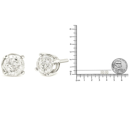 Pair of white metal stud earrings with round white gemstones in four-prong settings, shown from front and side angles, next to a ruler and a coin for size reference.