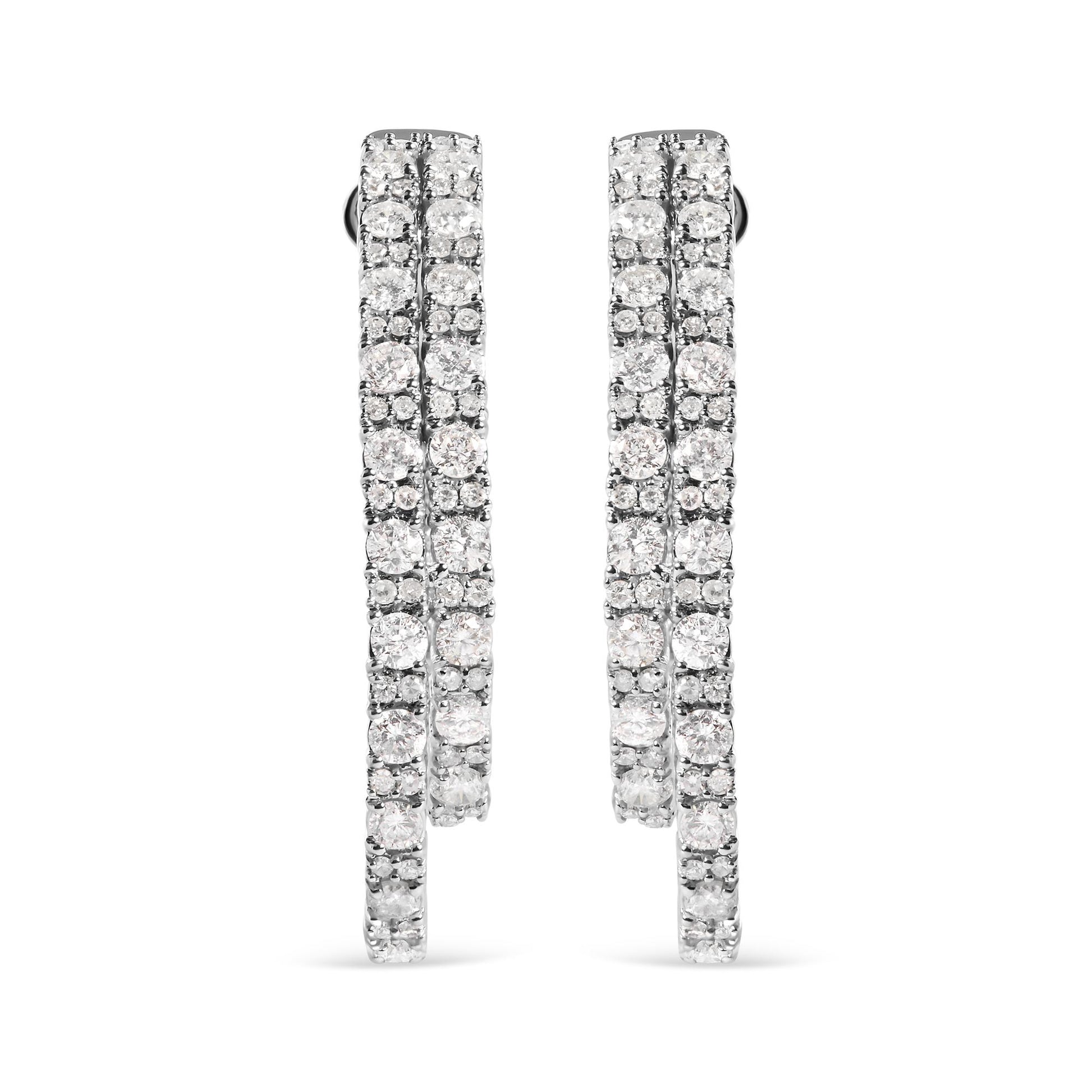 Front-facing view of a pair of white metal hoop earrings encrusted with multiple rows of round white gemstones in a prong setting.