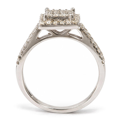 Close-up side view of a white metal ring with a square cluster of prong-set round white gemstones on top and additional white gemstones set along the band.