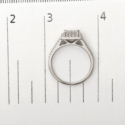 Top view of a white metal ring with round white gemstones in prong settings, shown on a measuring scale.