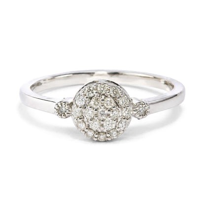 Close-up front angle of a white metal ring featuring a cluster of round white gemstones in prong settings at the center.