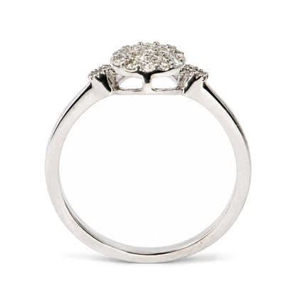Close-up side view of a white ring with a halo cluster of round white gemstones in prong settings on top.