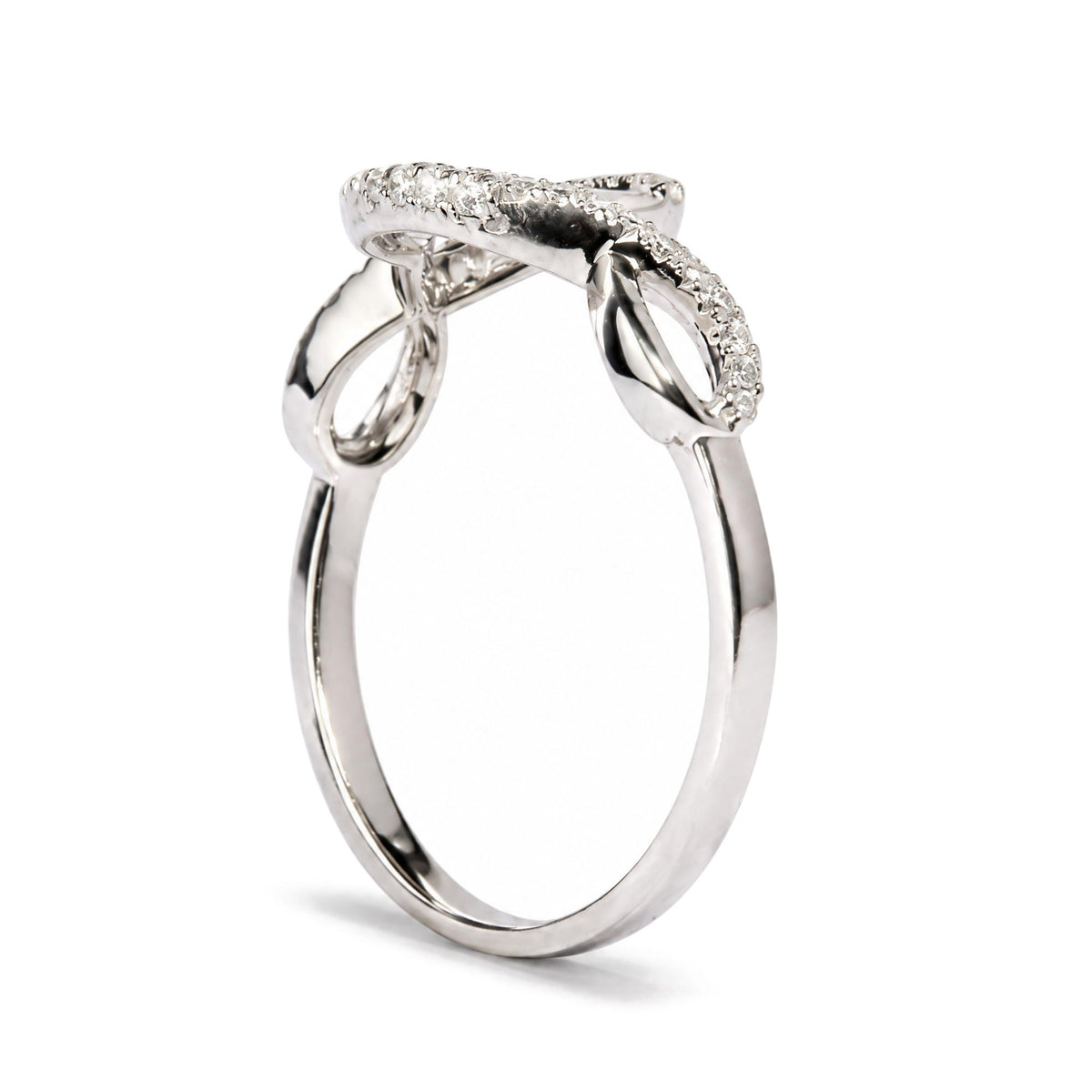 Close-up front angle of a white metal ring with a crossover design featuring round white gemstones in prong settings along the top curve, shown on a white background.