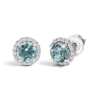 Pair of white metal stud earrings with round blue gemstones at the center, surrounded by round white gemstones in a shared prong setting, shown at an angled close-up.