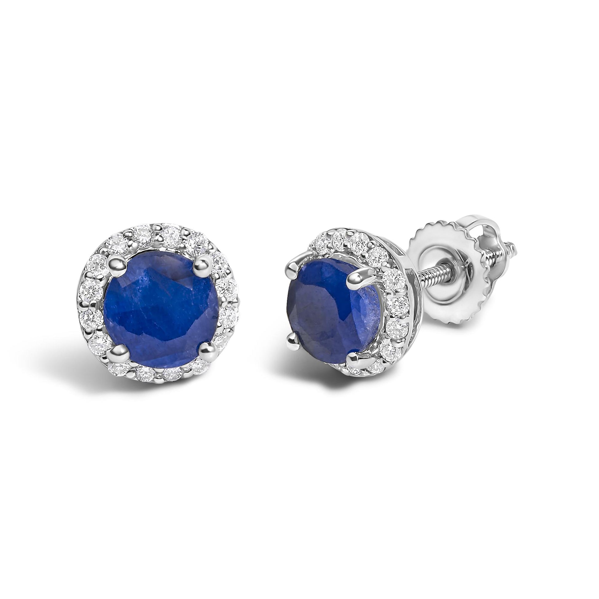 Pair of white metal stud earrings with a round blue gemstone center surrounded by a halo of small round white gemstones, shown in a close-up angled front and side view.