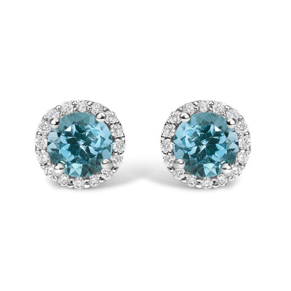 Pair of white metal round stud earrings with central blue round gemstones and surrounding white round gemstones in shared prong setting, shown in a front-facing angle.