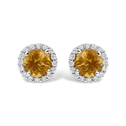 Pair of white metal stud earrings with round orange gemstones at the center, surrounded by a halo of small white gemstones, shown from a front angle on a white background.