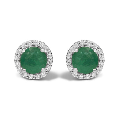 Front view of a pair of white metal stud earrings featuring round green gemstones in four-prong settings, each surrounded by a halo of small round white gemstones in shared prong settings.