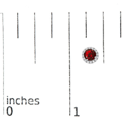 Earring with a round red gemstone center surrounded by a circle of small white gemstones, shown on a scale.