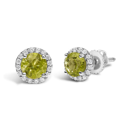 Pair of white metal stud earrings with round green gemstones in the center, surrounded by a circle of small white gemstones, shown from a front side angle on a white background.