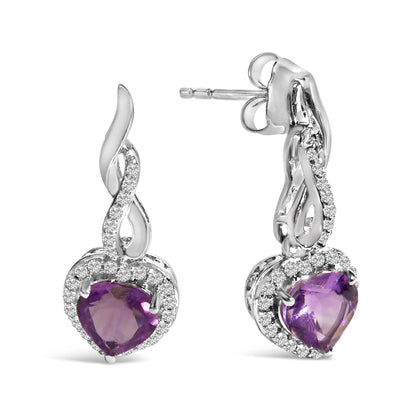 Pair of white metal earrings with heart-shaped purple gemstones surrounded by small white round gemstones, shown in close-up from a front and side angle.