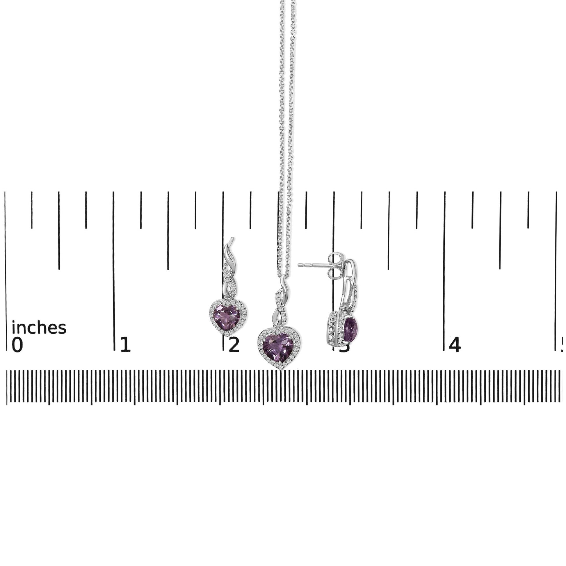 Set of white metal jewelry including a heart-shaped purple gemstone pendant necklace and matching earrings with round white gemstones, shown on a ruler scale from front and side angles.